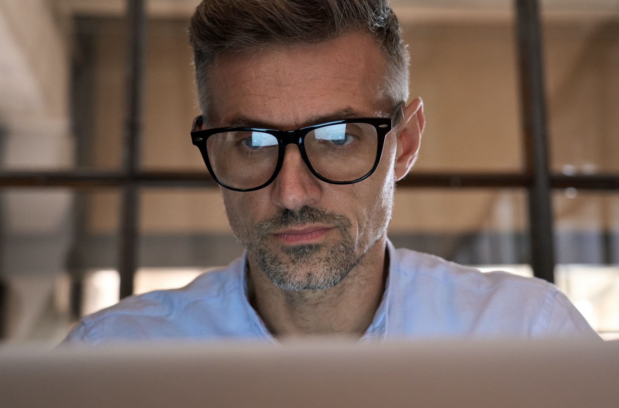 Concentrated business man looking at computer screen reflecting in glasses.
