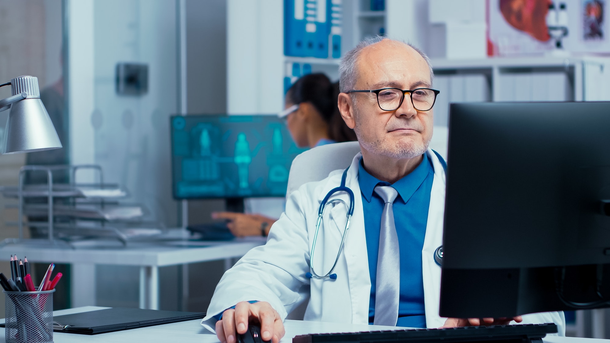 Elderly doctor working on PC