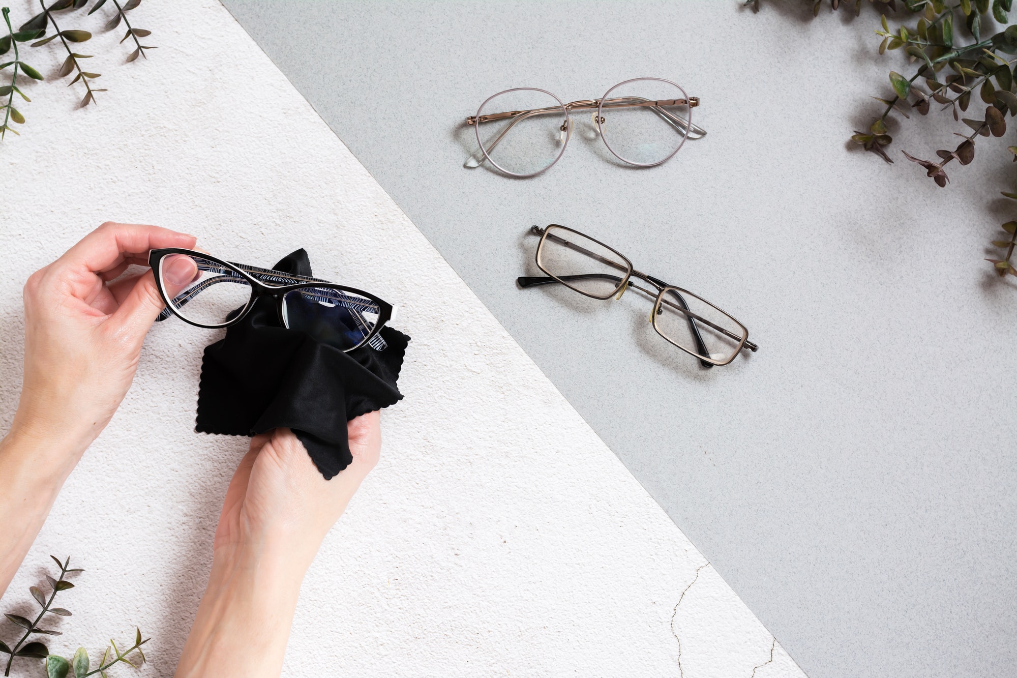Women's hands clean glasses with a cloth. Glasses for vision in a metal frame
